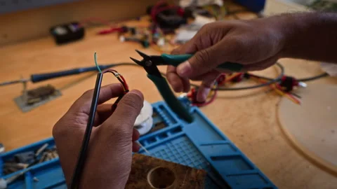 Man Cutting Wires with Pliers for Robot Assembly Stock Footage 343516118
