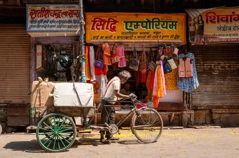 Man with cycle rickshaw in front of textile and bag shop with Hindi signage in Stock Photos
