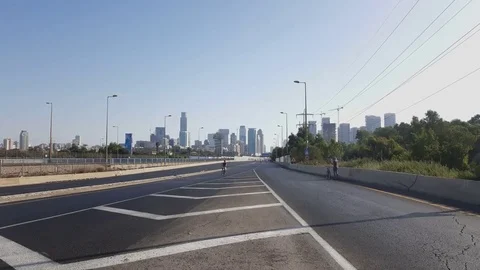 Man cycles on empty Ayalon Road, Yom Kippur, Tel-Aviv high rises in background Vídeos de archivo 80260006