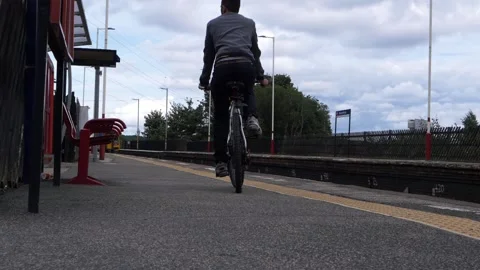 Man cycles on railway platform with train in distance Stock-Footage 161817268