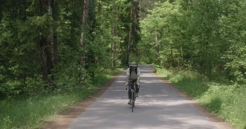 Man cycling through forest road on his way to work Stock Footage 312354926