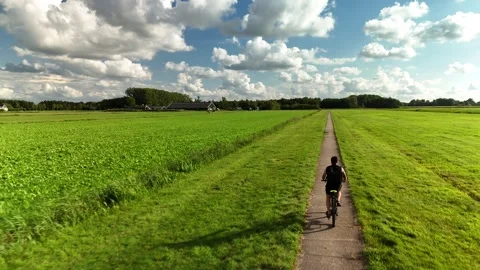Man Cycling Through Green Fields — 4K Drone Footage Stock Footage 317847336