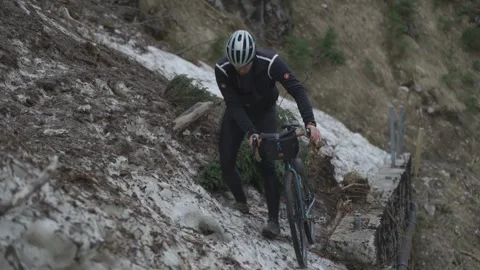 Man cyclist pulls bicycle through avalanche in mountains. Bicyclist is trapped Video stock 285054099