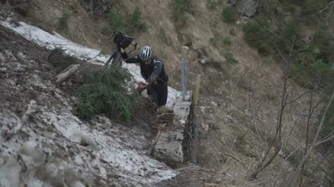 Man cyclist pulls bicycle through avalanche in mountains. Bicyclist is trapped Stock Footage 285054139