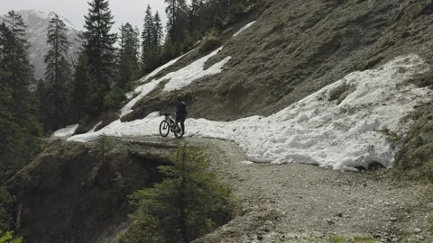 Man cyclist pulls bicycle through avalanche in mountains. Bicyclist is trapped Video stock 285054240