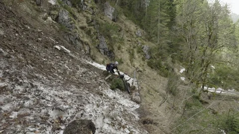 Man cyclist pulls bicycle through avalanche in mountains. Bicyclist is trapped Stock Footage 316640091