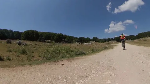 A man cyclist rides on a mountain path in a sunny morning, vr360 effect Stock Footage 113055871