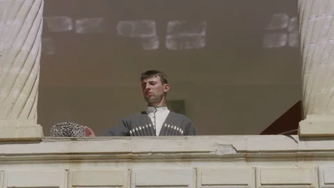 Man in Dagestan Circassian puts on hat standing on balcony Stock Footage 108167361