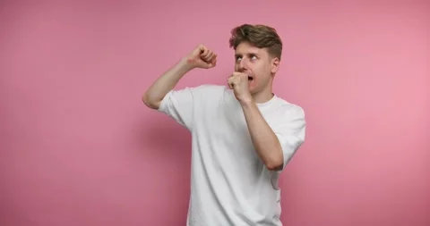 Man dances and shows different expressions in front of a pink wall in a stu.. 動画素材 328246981