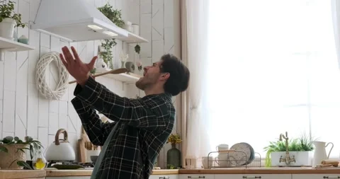 Man dances and sings in kitchen holding spatula Stock Footage 239454730