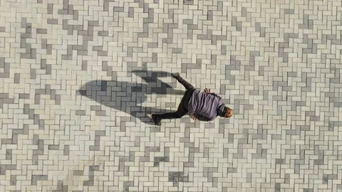 A man dances breakdancing against the background of street tiles. The dancer's Stock Footage 164913865