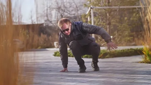 A man dances breakdancing on a street tile in the middle of the city background Stock Footage 164914199