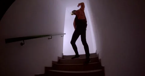 A man dances dynamically in a dark room, showcasing joy and confidence Stock Footage 313563767