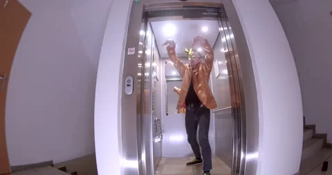 A man dances in an elevator, wears a mask, then chats on his phone Stock Footage 311817221