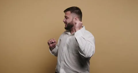 Man dances happily in front of a yellow background with joyful movements an.. Видео 326797886