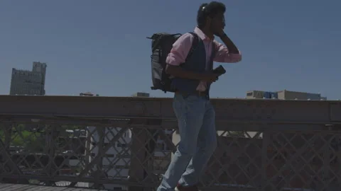 Man dances joyfully on bridge while listening to music with smartphone Stock Footage 312640633