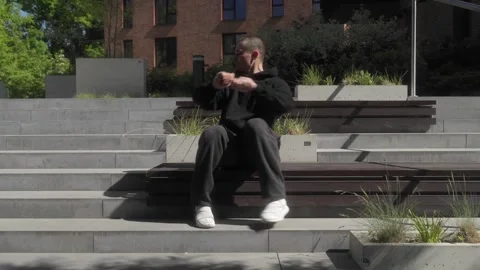 A man dances while sitting on a bench, performing hand and foot gestures. Stock Footage 286877653
