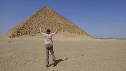 Man is dancing and jumping from happiness. On the background is The Red Pyramid. Stock Footage 256175780