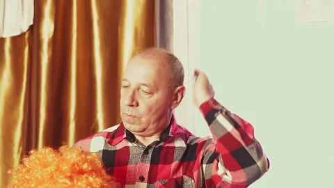 A man is dancing in a carnival wig with red curls Stock Footage 131752146