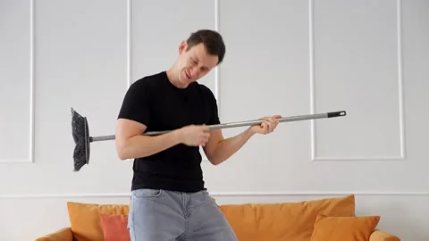 Man dancing with cleaning mop in living room Video stock 307440445