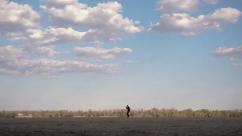 A man is dancing in distance.In background is forest and cloudy beautiful sky. Stock Footage 130727514