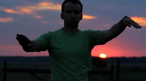 The man is dancing: does wave his arms on the background of a beautiful sunset Stock Footage 65025317