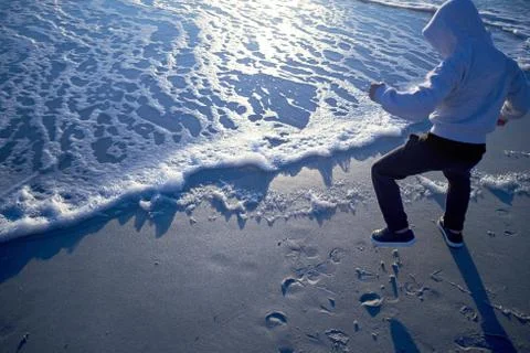 Man dancing at the edge of the surf at sunset Stock Photos