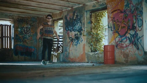 Man dancing in empty building with graffiti and looking straight at camera Stock Footage 117918557