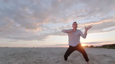 Man dancing freestyle dance on the sand at sunset. Slow motion. Gimbal shot Stock Footage 135610595