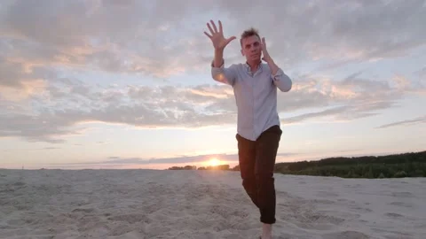 Man dancing freestyle dance on the sand at sunset. Slow motion. Gimbal shot Stock Footage 135610596