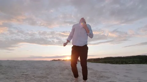 Man dancing freestyle dance on the sand at sunset. Slow motion. Gimbal shot Stock Footage 135610654
