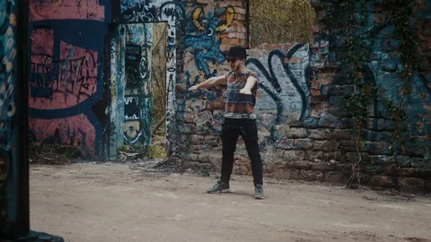 Man dancing in front of graffiti on wall in abandoned building Stock Footage 117916726