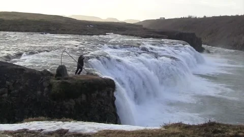 Man dancing in front of a waterfall in iceland in winter Stock Footage 259719886