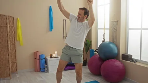 Man dancing joyfully in wellness center surrounded by exercise equipment an.. Video stock 298135692