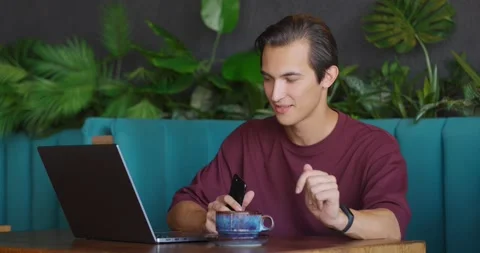 Man dancing with mobile phone in his hand while working remotely in coffee shop Stock Footage 165074991