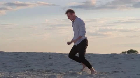 Man dancing modern ballet on the sand at sunset. Slow motion Stock Footage 135611607