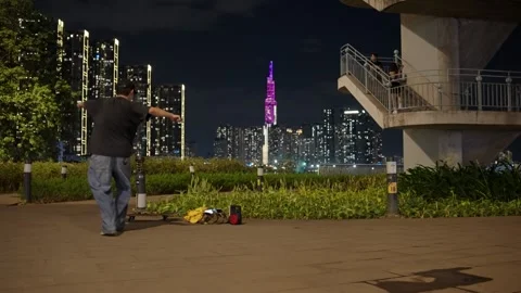 Man Dancing In The Park At Night With City Skyline In Background. District 1 Of Stock Footage 331599879