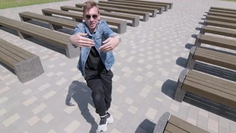 Man dancing street modern dance in a park between rows of benches. Slow motion Stock Footage 132659919