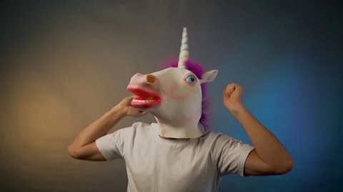 The man dancing in the unicorn mask on gray background Stock Footage 129101279