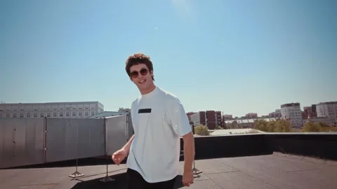 Man dancing on urban rooftop with cityscape in the background. energetic and Stock Footage 345152920