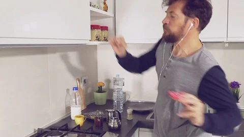 Man dancing while preparing coffee in kitchen in pajamas eating donut closeup Stock Footage 74971307