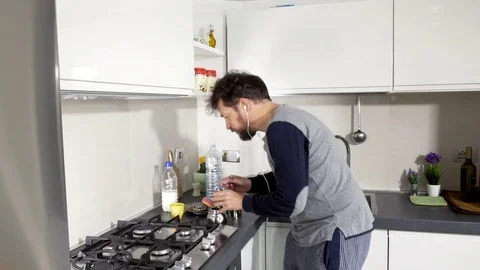 Man dancing while preparing coffee in kitchen in pajamas wide shot Stock Footage 74977835