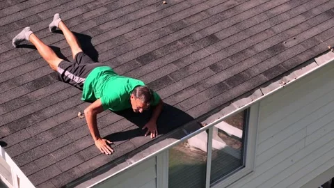 Man Dangerously Cleans Gutter From Roof   Stock Footage 345600009