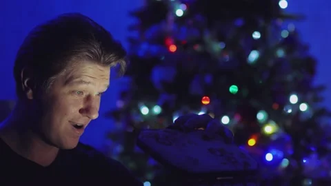 A man in the dark against a background of lights opens a gift Stock Footage 146363335