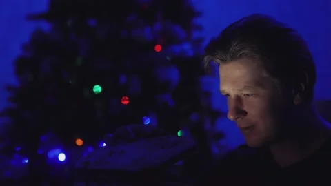 A man in the dark against a background of lights opens a gift Stock Footage 146363706