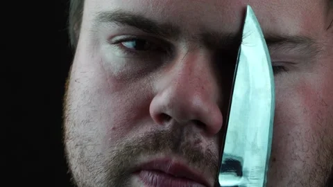 Man on dark background holding a knife near the face Stock Footage 130222383