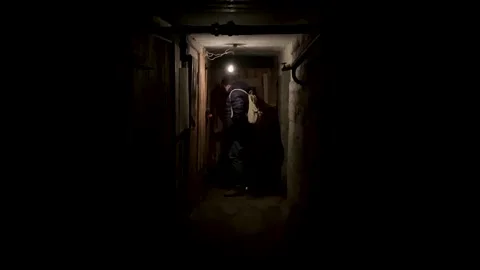 A man in a dark basement closes the door with a padlock and leaves Vidéo 170724029
