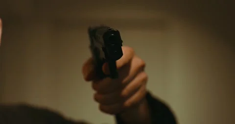 A man in dark clothes points a gun into the camera close up Stock Footage 300668716