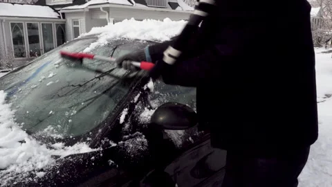 Man in Dark Coat removes Ice from a Black Car Stock Footage 147693807