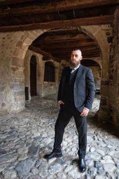 Man in dark elegant suit posing under the arcades Stock Photos